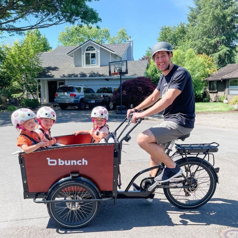 Dad riding a Bunch Bike with three kids in the front bucket